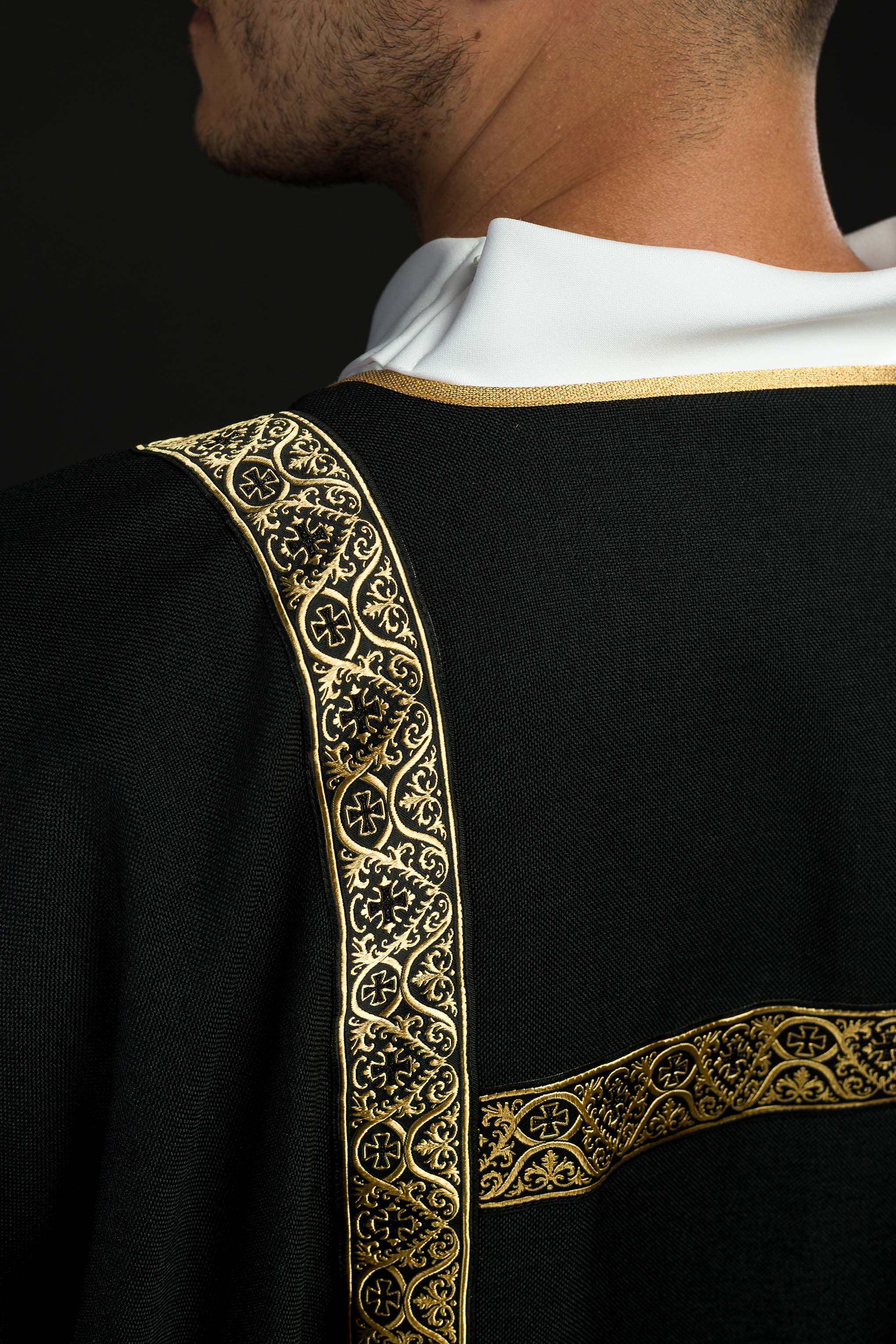 Dalmática negra decorada con cintas de jacquard doradas