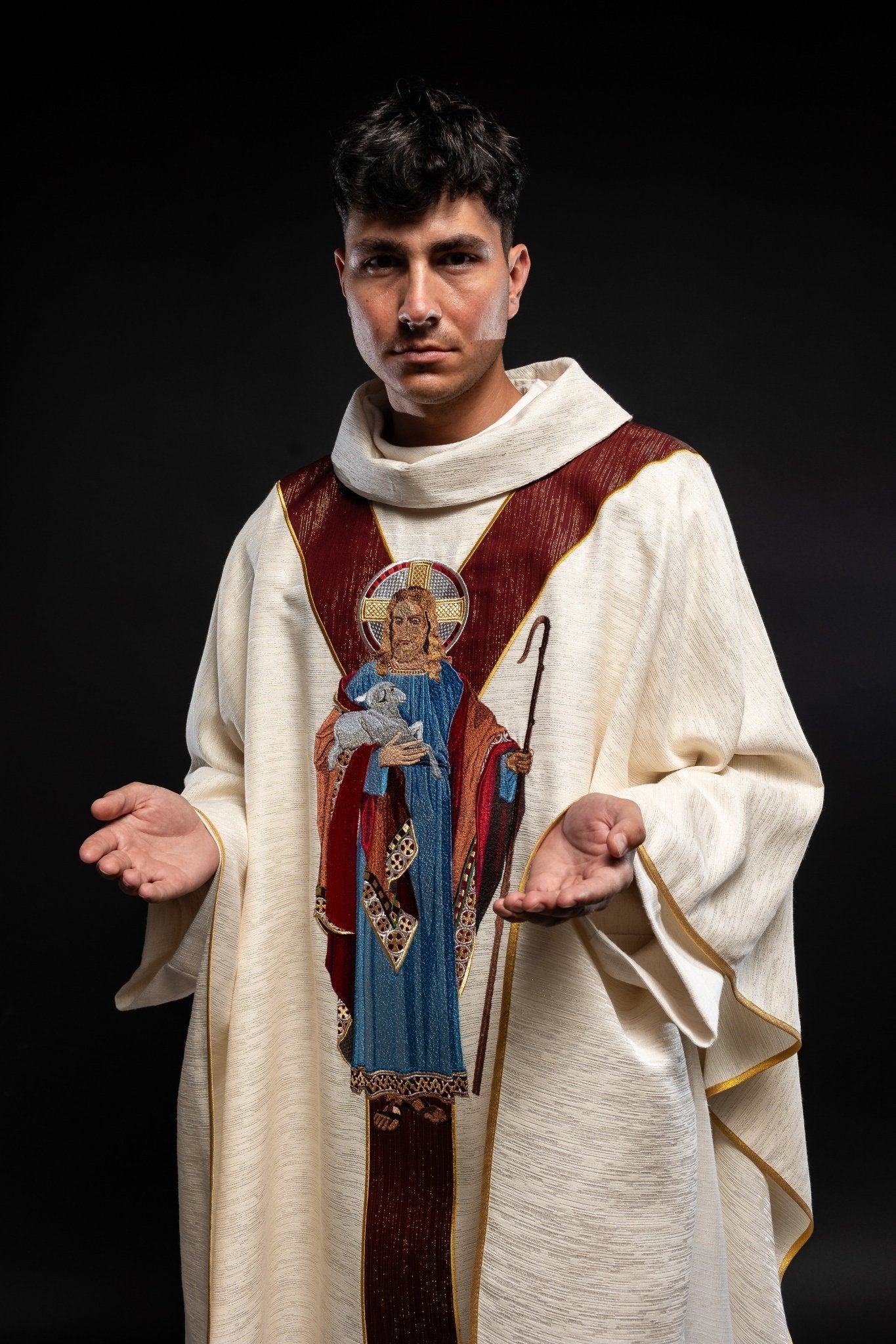 Casulla de color crudo con la imagen de Jesús Buen Pastor con una franja decorativa de color burdeos. LE/7035/05 - CASULLAS.ES