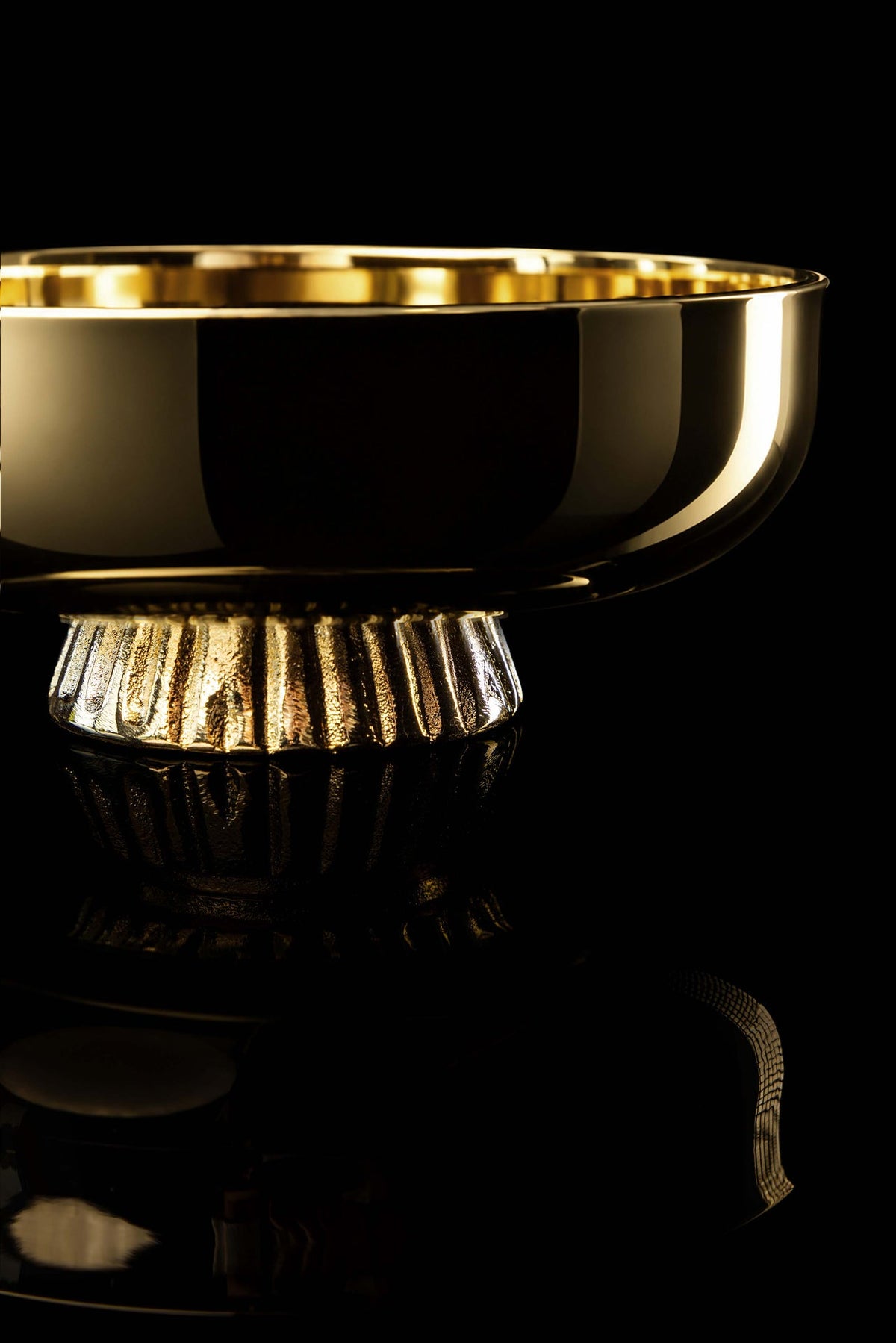 Patena bañada en oro en primer plano, con base decorativa acanalada