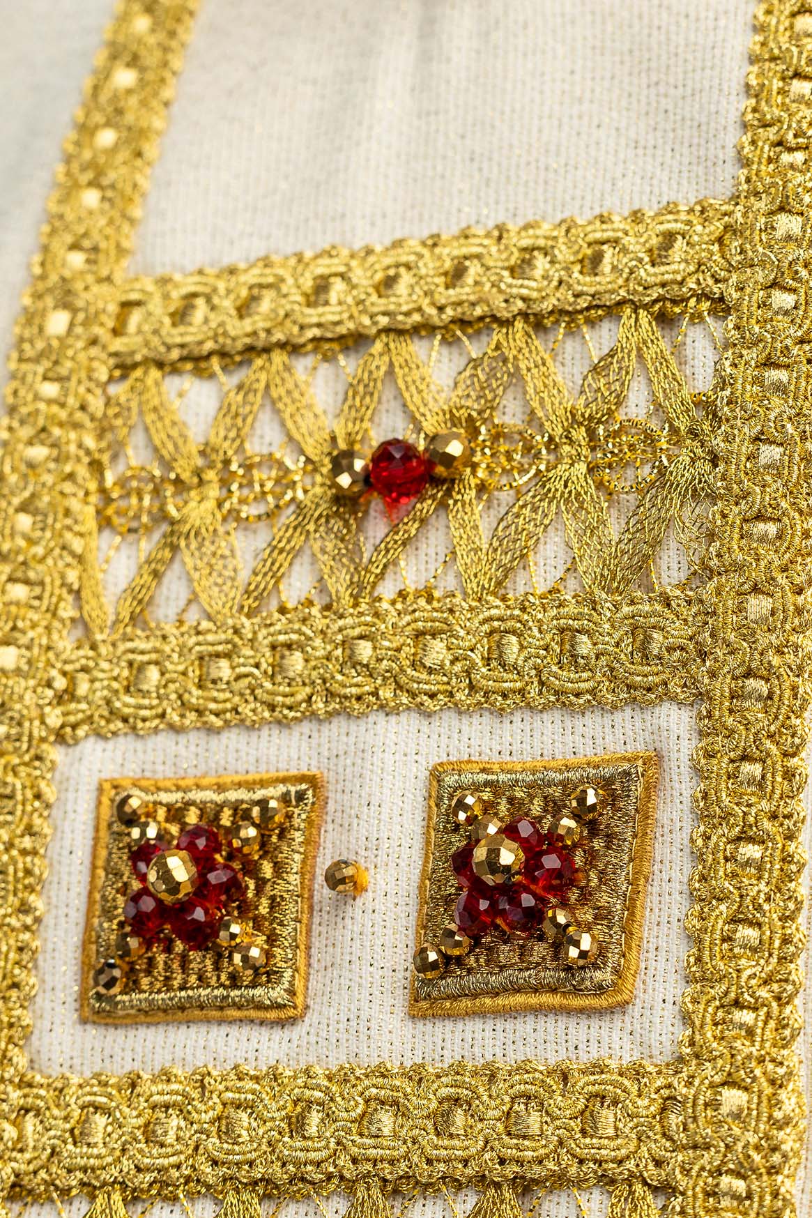 Casulla con detalle del galón central dorado, bordado calado y piedra roja