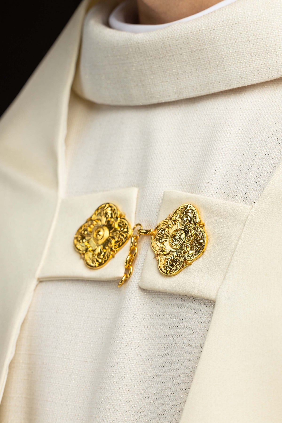 Velo humeral crudo en detalle, con broche dorado ornamental de unión