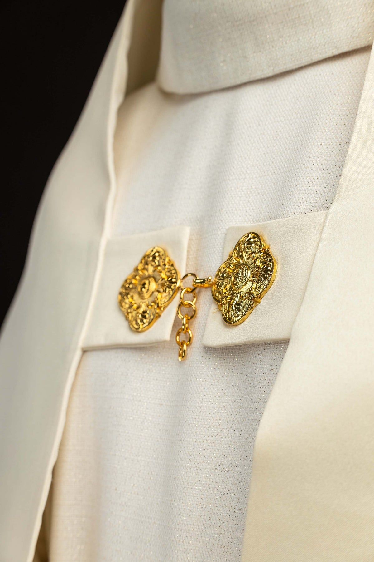 Velo humeral crudo en detalle, con cierre de broches ornamentales dorados y cadena