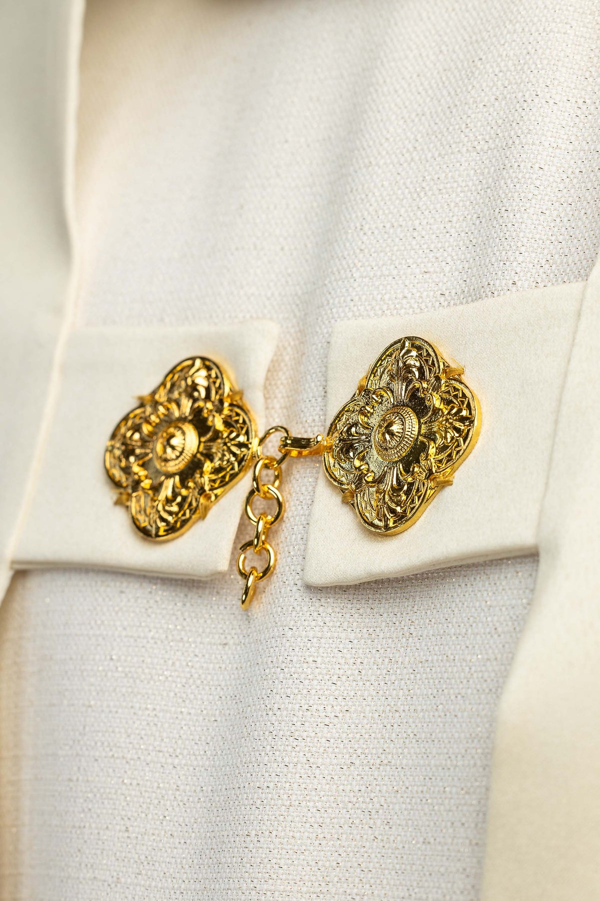 Velo humeral crudo, detalle del cierre con broches ornamentales dorados