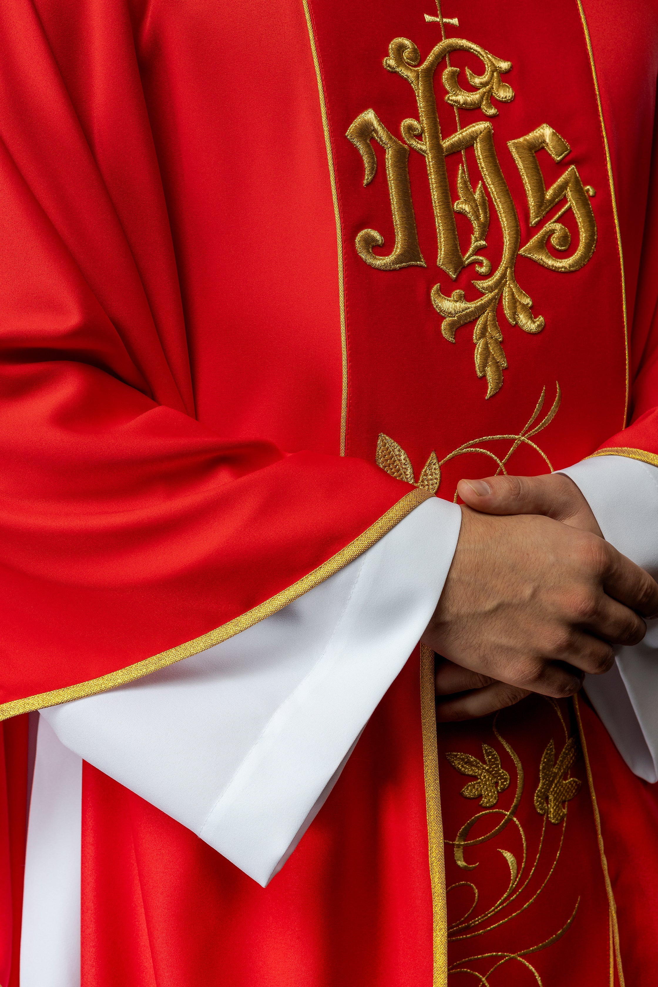 Casulla litúrgica roja con cinturón ricamente decorado con motivos florales e IHS