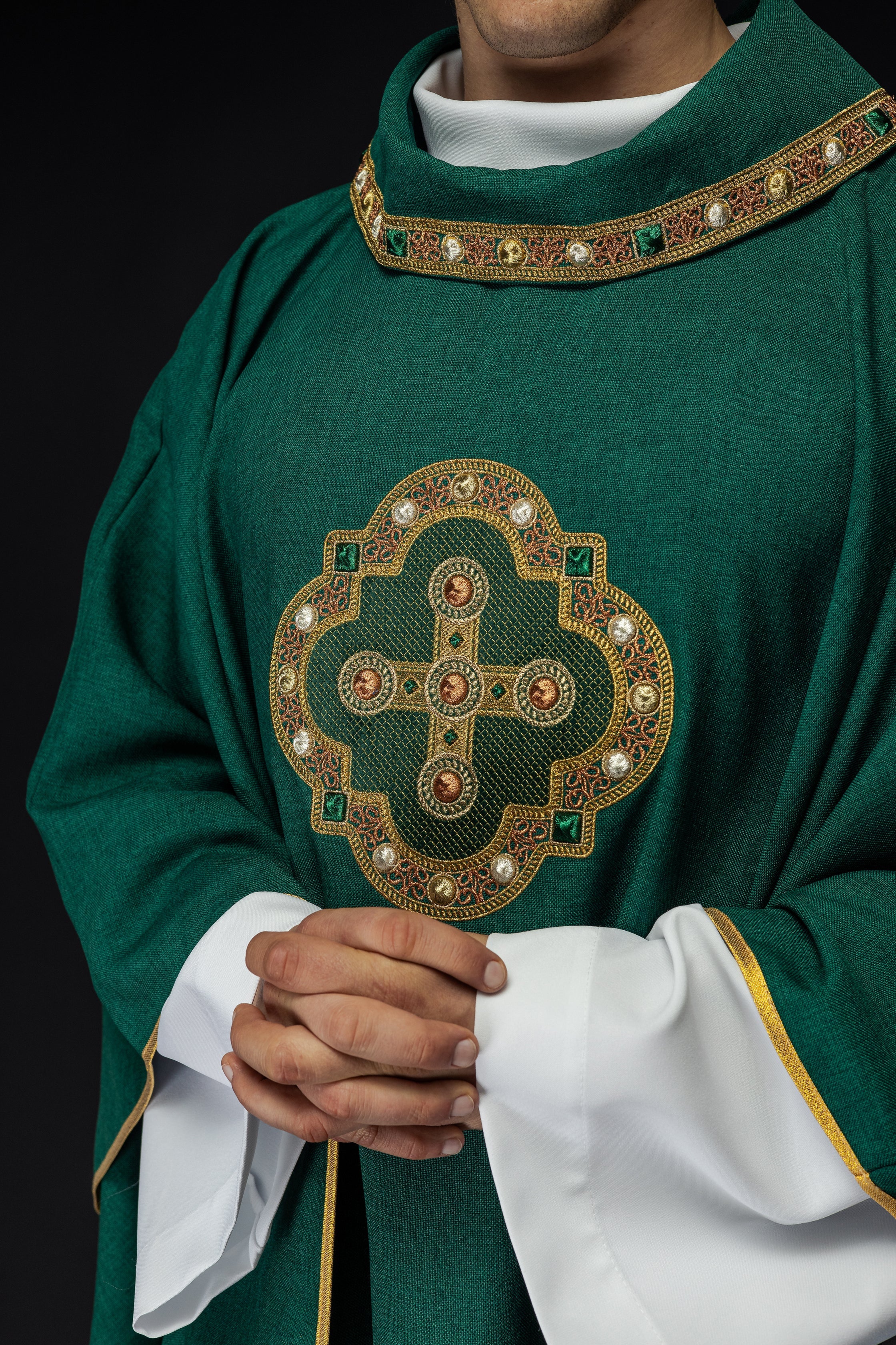 Casulla de color verde con ribetes bordados en el cuello y alrededor del bordado de la cruz