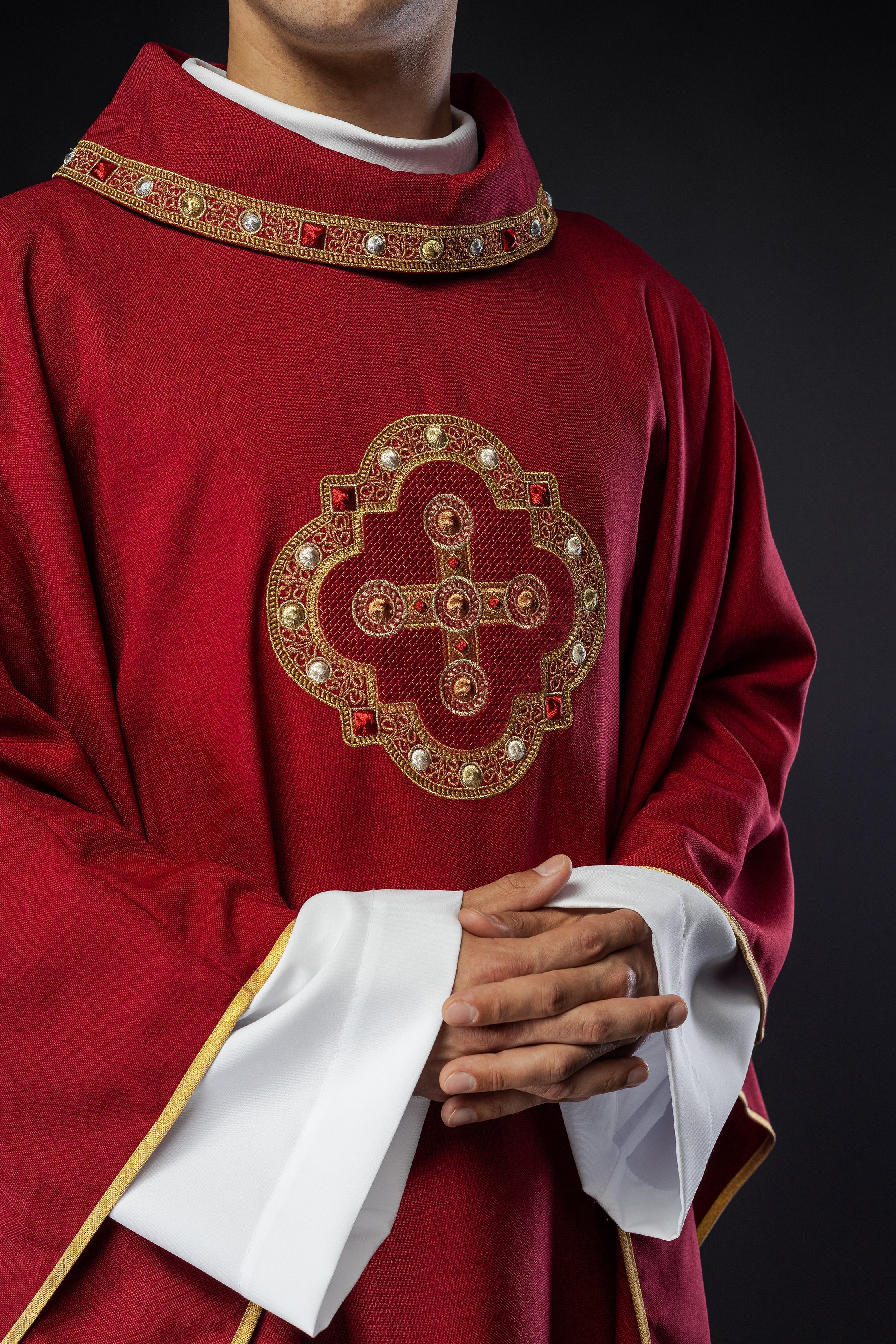 Casulla roja con ribetes bordados en el cuello y alrededor del bordado de la cruz