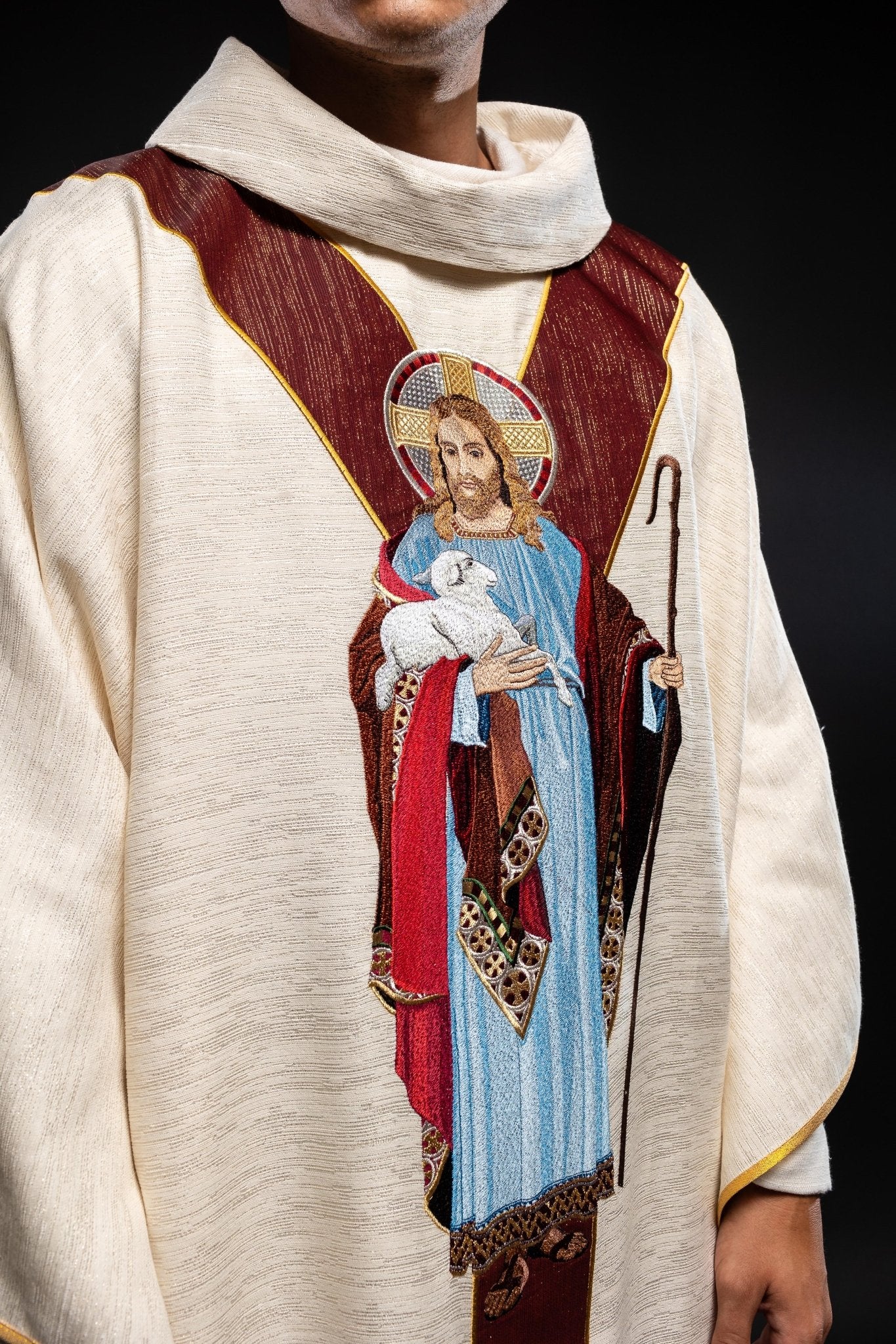 Casulla de color crudo con la imagen de Jesús Buen Pastor con una franja decorativa de color burdeos. LE/7035/05 - CASULLAS.ES