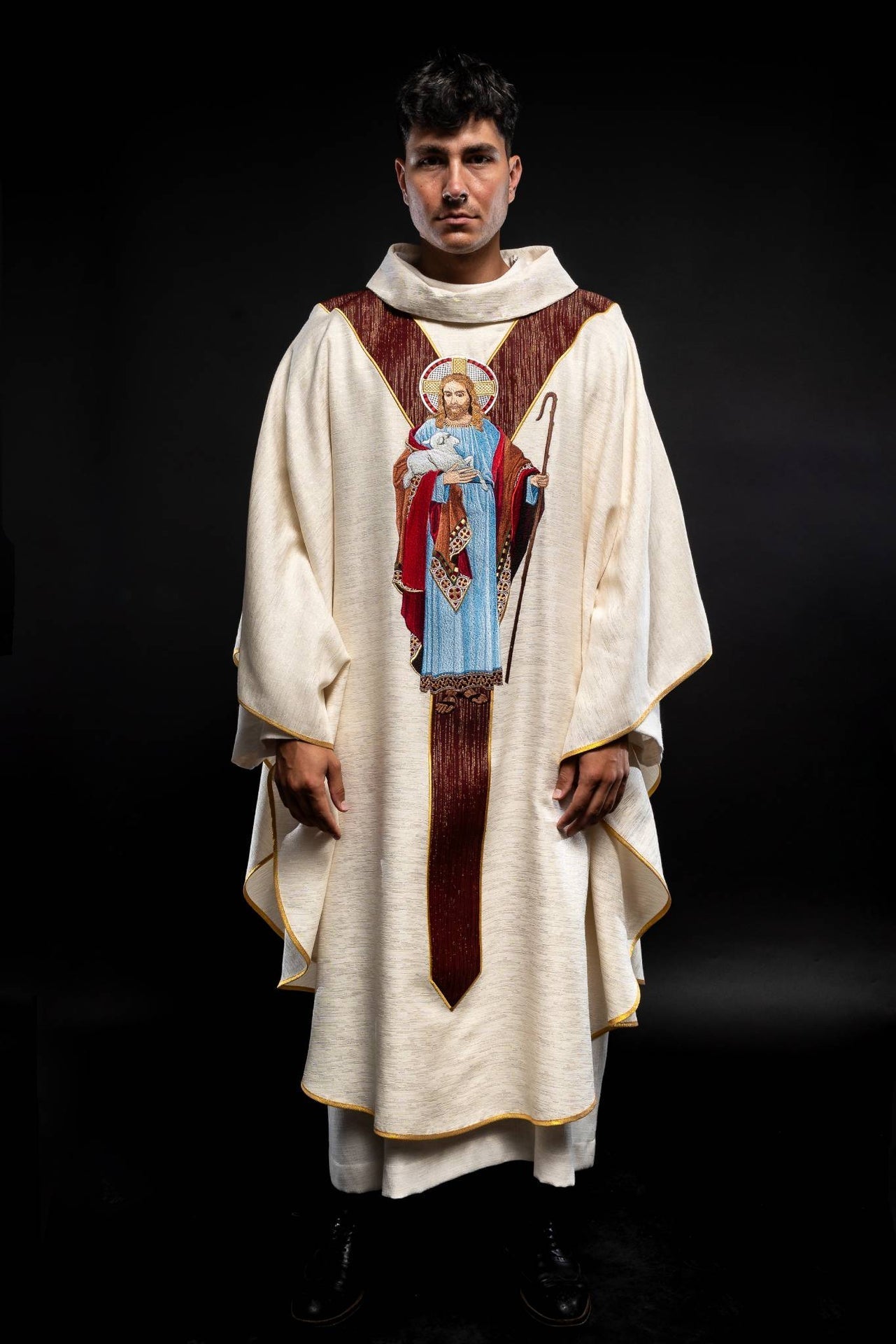 Casulla de color crudo con la imagen de Jesús Buen Pastor con una franja decorativa de color burdeos. LE/7035/05 - CASULLAS.ES