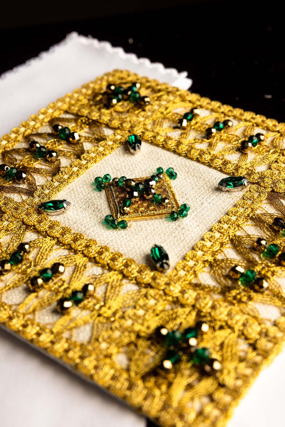 Juego de altar, primer plano del medallón central dorado con piedras verdes y negras