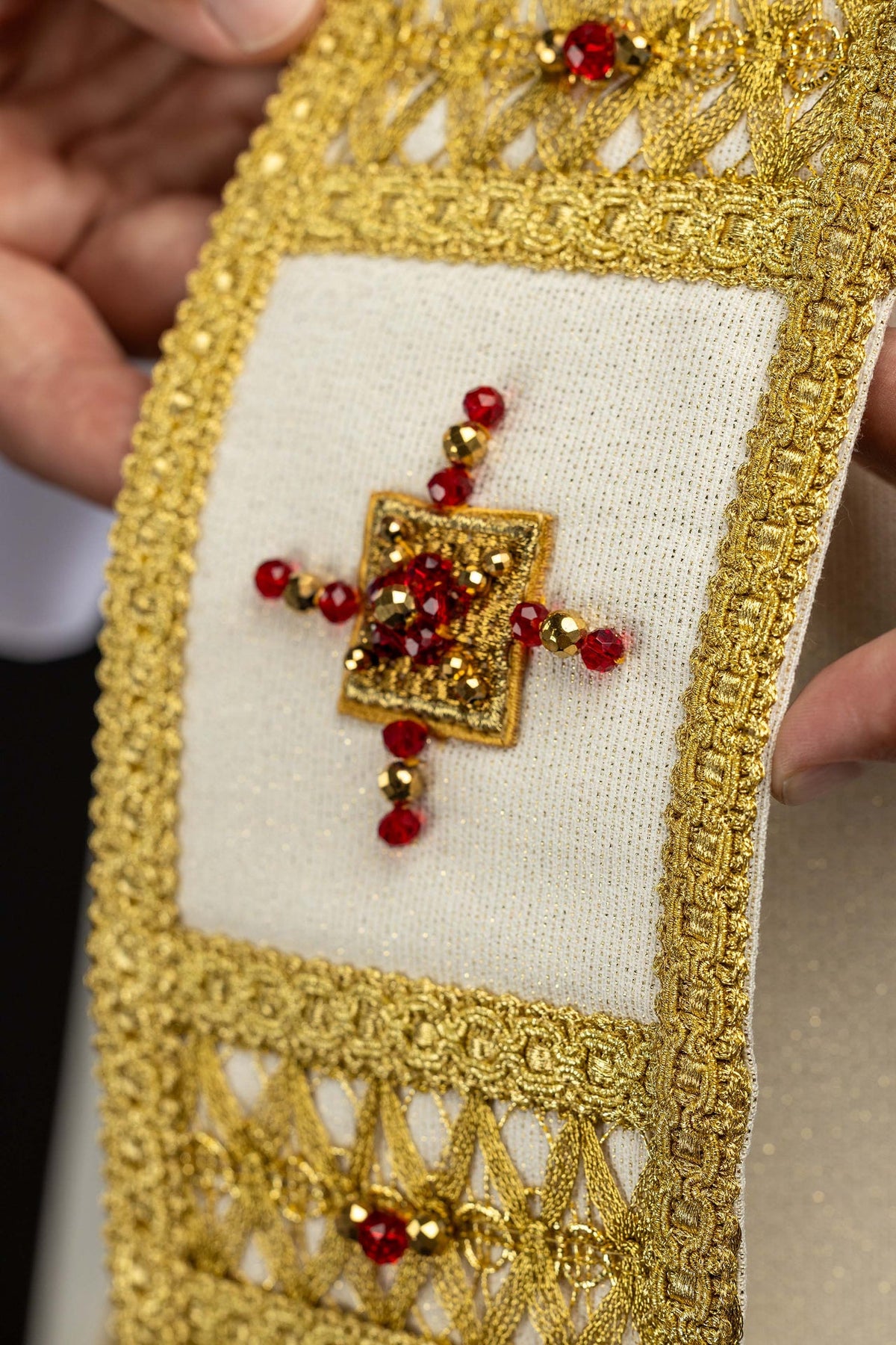 Casulla con detalle de cruz bordada y piedras rojas en el galón central